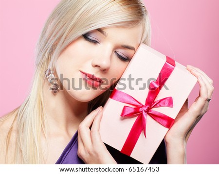 portrait of beautiful blonde party girl with closed eyes holding birthday gift box on pink
