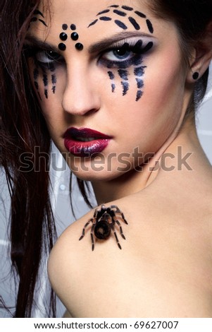 portrait of girl with spider bodyart of face zone posing with real spider Brachypelma smithi on her shoulder