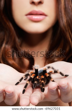 close-up portrait of girl with brachypelma smithi spider. girl's hands with spider in focus, face out of focus.