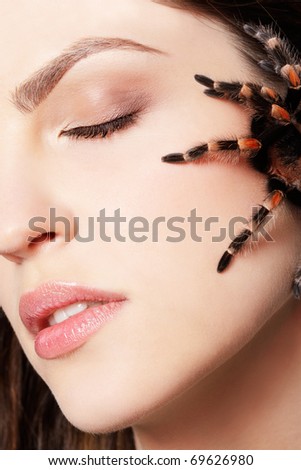 close-up portrait of girl with brachypelma smithi spider creeping over her face