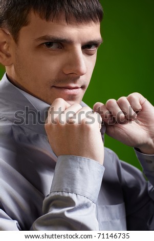 sideview headshot portrait of young handsome brunet guy in gray shirt checking collar on green