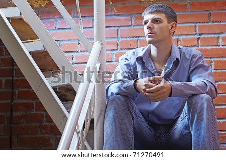 portrait of young handsome brunet guy posing near red brick wall