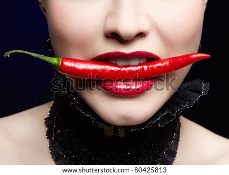close-up portrait of beautiful girl\'s lower part of face biting spicy hot red cayenne chili pepper