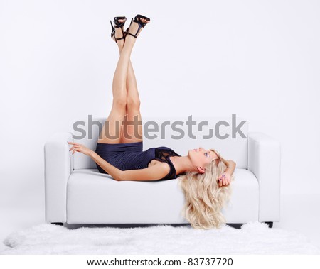 full-length portrait of beautiful young blond woman on couch streching legs in court shoes