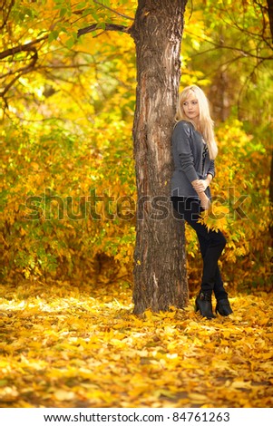 Autumn woman under tree in park with fall leaves