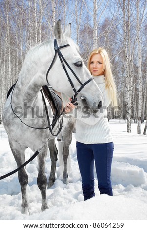 outdoor portrait of beautiful blonde girl with pale horse in sunny winter forest