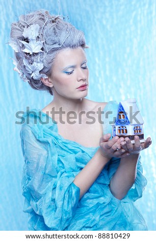 fantasy portrait of beautiful young woman imaging ice fairy on frozen blue with toy house