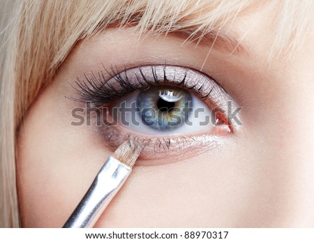 close-up body part portrait of beautiful woman\'s eye make up with cosmetic brush