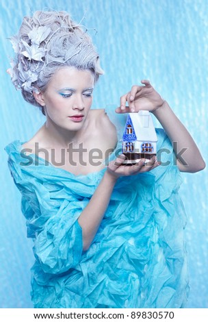 fantasy portrait of beautiful young woman imaging ice fairy on frozen blue with toy house