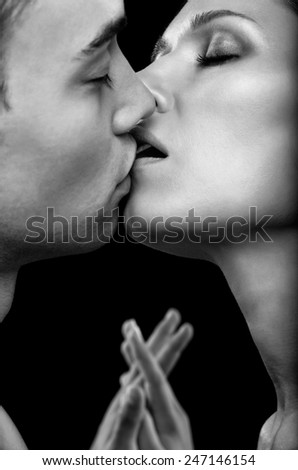 Young couple of lovers kissing on black background