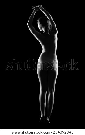 Silhouette of nude beautiful young woman from back side with hands up isolated on black