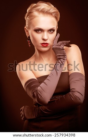 Young blonde woman in black dress and long gloves on dark background toned in marsala color
