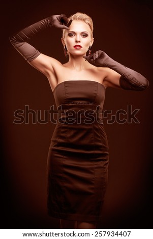 Young blonde woman in black dress and long gloves on dark background toned in marsala color