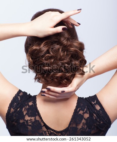 Young beautiful woman in black dress from back side on gray background