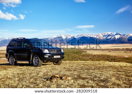 KURAI, RUSSIA - MAY 27, 2015: Black Land Cruiser Prado in Altai mountains in Kurai area with North Chuisky Ridge on background.