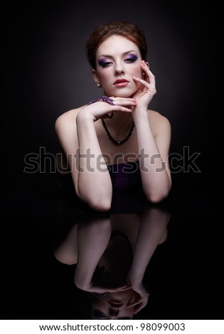 portrait of beautiful young red-haired woman sitting at dark mirror table