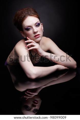 portrait of beautiful young red-haired woman at dark mirror surface