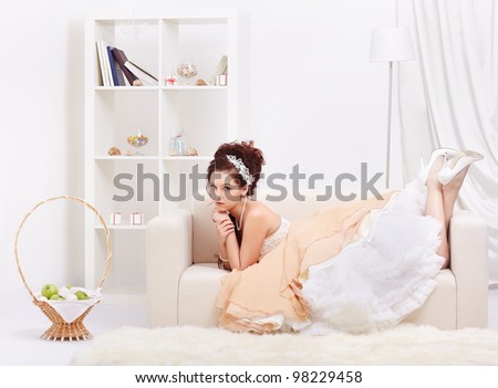 portrait of young beautiful retro woman in skirt with petticoat and corset lying on sofa in vintage flat