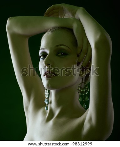 green tinted portrait of beautiful young blonde woman in ear-rings putting hands over her head