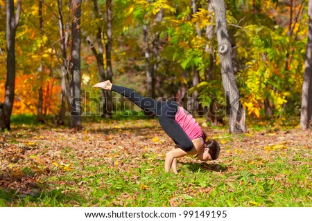 Woman exercises in the autumn forest yoga galavasana pose