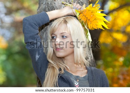 Young woman with a bouquet of leaves on a background of autumn park