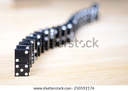black domino bone placed on a wooden surface in the queue. The Domino Principle.
