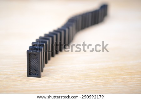 black domino bone placed on a wooden surface in the queue. The Domino Principle.