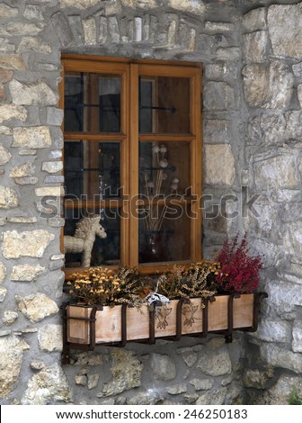 Ancient stone building window with everlasting flowers in flower box
