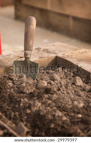 A dirty old trowel standing in the corner of an earth bed
