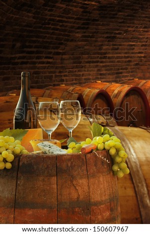 Wine cellar with glasses of white wine against wine barrels