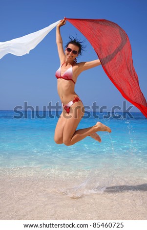 Happy Girl jumping on the beach with  scarfs
