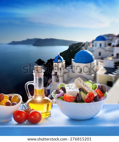 Greek salad against church in Oia village, Santorini island in Greece