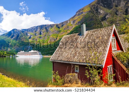 Red cottage against cruise ship in fjord, Flam, Norway