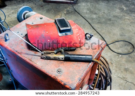 Red welding helmet with wire clamp instrument