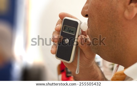 alcohol testing, man blowing in breathalyzer