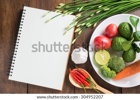 Recipe notebook, tomatoes, Red chilli, garlic and lemon on wood texture background