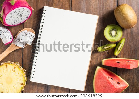 Recipe notebook, dragon fruit, kiwi, watermelon, Pineapple on wooden table.