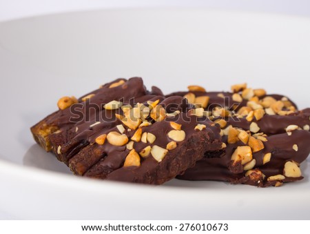 Tasty bananas covered by chocolate and nuts