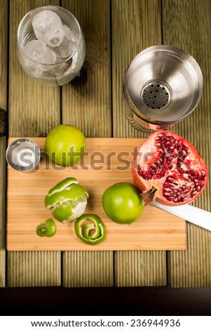 Mojito cocktail preparation, fruits, shaker, cutting board and a glass full of ice
