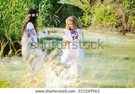 two girls in the Ukrainian national clothes swimming in the river.