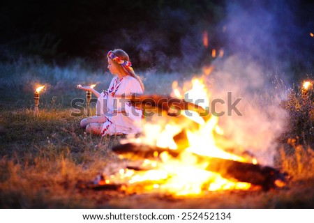 Ukrainian girl with a wreath of flowers on her head against a background of fire