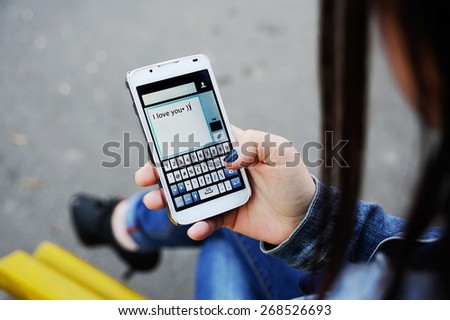Girl dials sms message on mobile phone
