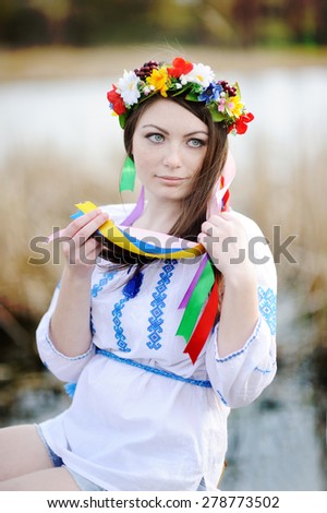 Ukrainian girl in a shirt and a flower wreath on his head on a background of the river
