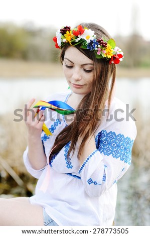 Ukrainian girl in a shirt and a flower wreath on his head on a background of the river