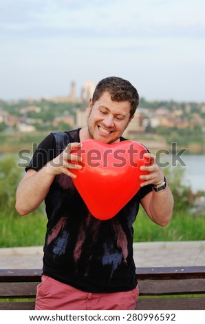 the man clenches with anger heart. Balloon in the shape of a heart in the hands of men