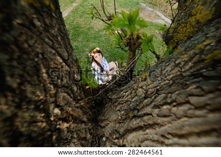 Ukrainian girl in a shirt and a wreath of flowers on her head under the tree