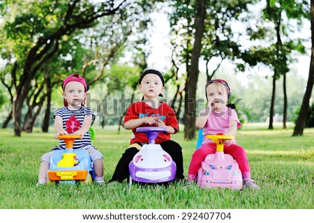 little boy and two little girls driving toy cars