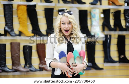 pretty girl holding a lot of colorful shoes. shopaholic woman chooses shoes