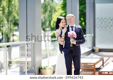 bride embraces the groom\'s shoulder. The bride with a wedding bouquet of orchids