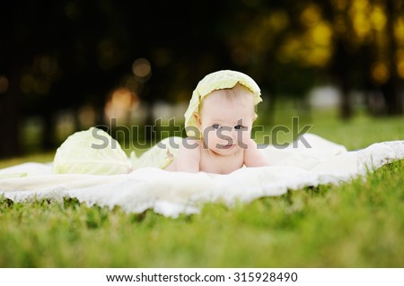 baby girl with cabbage. Cabbage leaves on the head of a child.